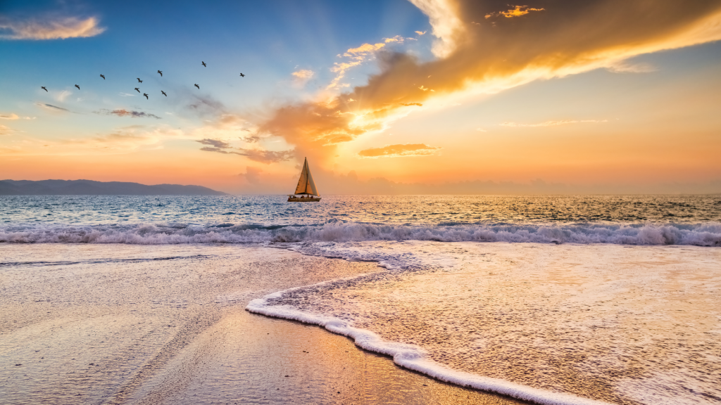 Algarve beach view at sunset with sailboat in the distance