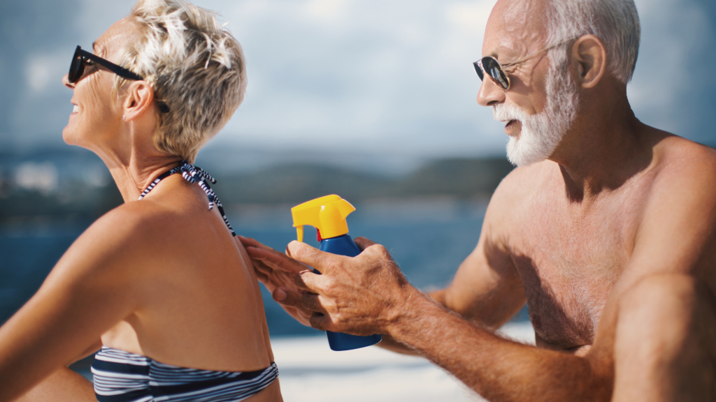 mature couple on beach putting on sunscreen